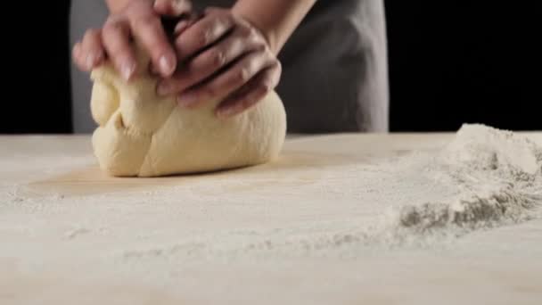 黒を背景に小麦粉のヒープの近くの木製のテーブルの上に生地をこねるプロのパン屋 おいしいピザを調理する概念 撃たれた — ストック動画