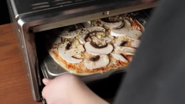 プロのシェフが調理のためのオーブンでキノコとチーズとピザを置きます おいしいピザを作るというコンセプト 撃たれた後 — ストック動画