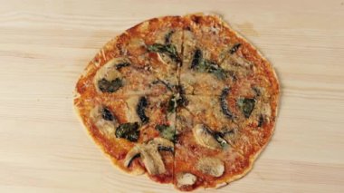 Kızın eli, mantarlı, peynirli, fesleğenli ve parmesanlı bir dilim pizzayı ahşap masadan alır. Lezzetli pizza pişirme kavramı. Üst Manzara. 4K