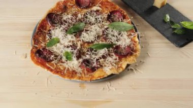 Profesyonel şef, tadını arttırmak için taze yeşil fesleğen yaprağını salam pizzasının üstüne koyar. Lezzetli pizza pişirme kavramı. Üst sıradaki atış. 4K