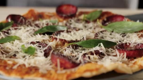 プロのシェフが新鮮な緑のバジルの葉をサラミピザの上に置き 味を高めます おいしいピザを調理する概念 閉めろ — ストック動画