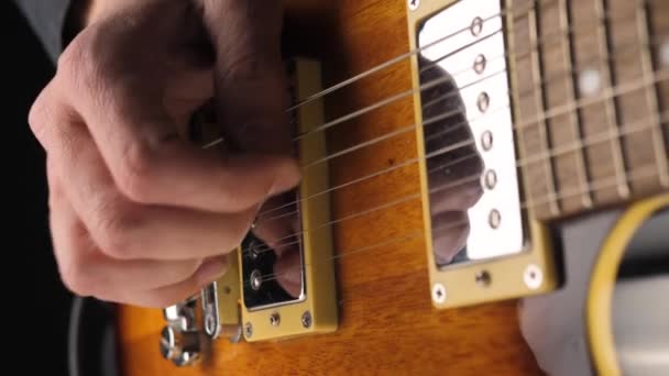 Gitarrist Spielt Eine Hellbraune Sechssaitige Gitarre Mit Pickel Vor Schwarzem — Stockvideo