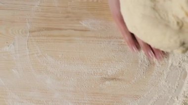 Profesyonel fırıncı hamuru un yığınının yanındaki ahşap bir masada yoğurur. Evde kalma ve lezzetli pizza pişirme kavramı. Üst Manzara. 4K