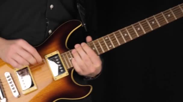 吉他手在黑色背景下弹奏浅褐色六弦电吉他 呆在家里做一些音乐的概念 自由时间的音响艺术 — 图库视频影像