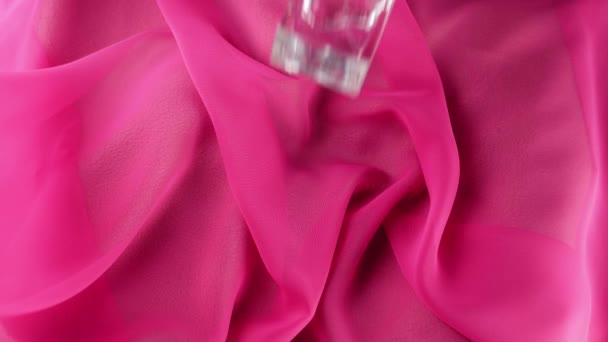 用青色香水或精油装饰的扁平瓶子落在粉色面料的背景上 香气和气味的概念 慢动作 — 图库视频影像