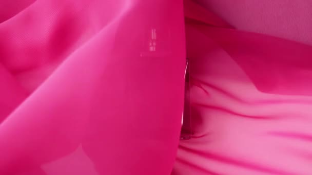 シアン香水やエッセンシャルオイルとフラット表面ボトルはピンクの布にあります ピンクの布が周りにはまり ボトルの周りを波 香りと香りの概念 閉めろ スローモーション — ストック動画