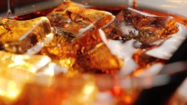 Kamera, siyah arkaplana karşı siyah saman ve kahverengi röfleli bir bardak kolayla buz küplerinden aşağıya doğru hareket ediyor. Kola ya da gazoz içmek, rahatlamak ve eğlenmek. Kapatın. 4K