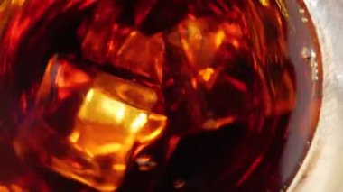 Buz küpleri siyah arka planda kahverengi röfleli bir bardak kolada kabarcıklarla yüzer ve döner. Kola ya da gazoz içmek, evde rahatlamak ve eğlenmek. Kapatın. Üst Manzara. 4K