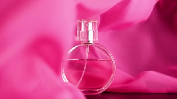 有粉色香水或精油的椭圆形表面瓶子放在桌上 粉红织物在空气中摇曳 在瓶子周围摇曳 香气和气味的概念 靠近点慢动作 — 图库视频影像