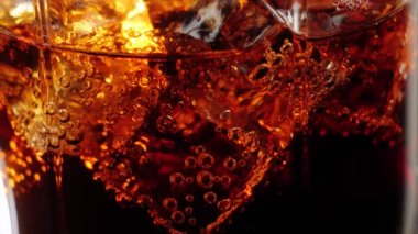 Kamera, siyah arkaplana karşı siyah saman ve kahverengi röfleli bir bardak kolayla buz küplerinden yukarıya doğru hareket ediyor. Kola ya da gazoz içmek, rahatlamak ve eğlenmek. Kapatın. 4K