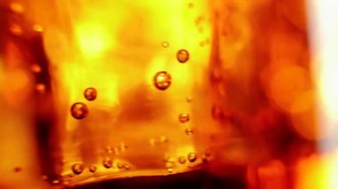 Buz küpleri siyah arka planda kahverengi röfleli bir bardak kolada kabarcıklarla yüzer ve döner. Kola ya da gazoz içmek, evde rahatlamak ve eğlenmek. Kapatın. 4K