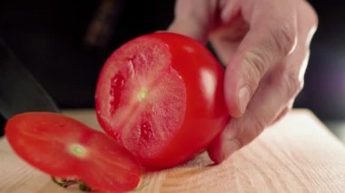 Profesyonel aşçı, keskin bir bıçakla tahta tahtada taze kırmızı domates dilimliyor. Caprese salatası malzemesi kavramı - domates, mozzarella, roka, yağ ve tuz. Kapat.