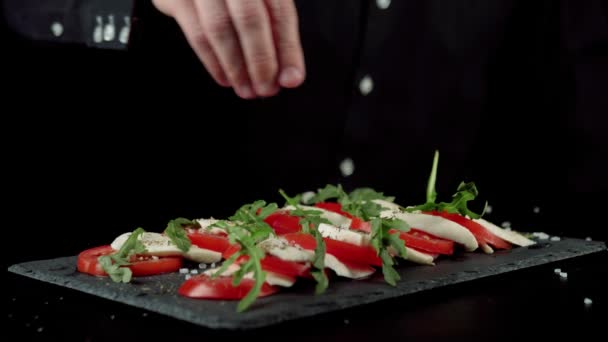 Chef Profissional Polvilha Uma Salada Caprese Pronta Com Sal Sal — Vídeo de Stock