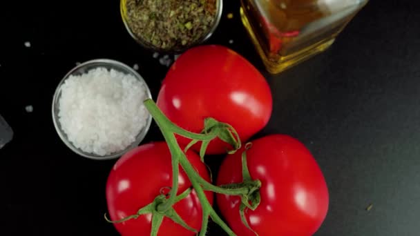 現代のカプレーゼサラダ ブランチに新鮮なジューシーな赤いトマト オリーブオイル 黒テーブルの上に海塩と地中海のハーブ カメラはトマトを回転させる トップ表示 — ストック動画