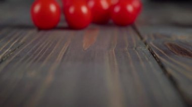 Yaz salatası. Taze sulu kırmızı kiraz domatesleri ahşap bir masada yuvarlanıyor. Taze yaz salatası yapma fikri. Kapatın. 4K