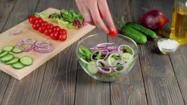 Yaz salatası. Profesyonel şef taze vişneli domatesleri cam kaseye koyar. Salatadan, kiraz domatesinden, salatalıktan ve soğandan taze yaz salatası yapma fikri. Orta atış. 4K