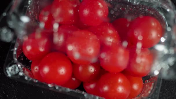 相机滑出塑料容器与樱桃西红柿 新鲜多汁的樱桃西红柿在木制桌子上的一块黑色板子上 制作夏季新鲜沙拉的概念 顶部视图 靠近点4K — 图库视频影像