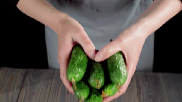 夏天沙拉 女人把几个新鲜多汁的绿色黄瓜放在一张木制桌子上的黑色板子上 放在相机的焦点上 制作夏季新鲜沙拉的概念 — 图库视频影像