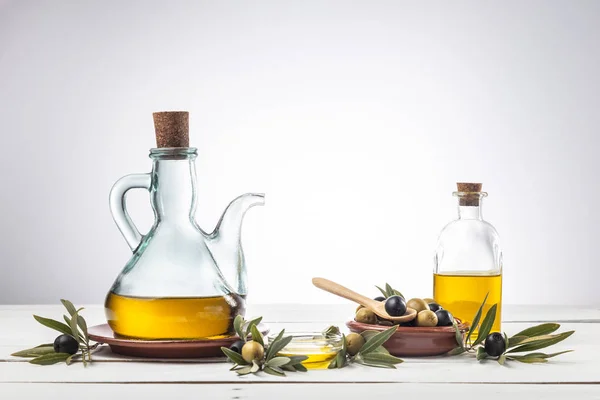 橄榄油和木桌上的橄榄枝 — 图库照片