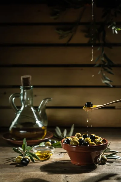 Olijfolie en de olijftak op de houten tafel — Stockfoto