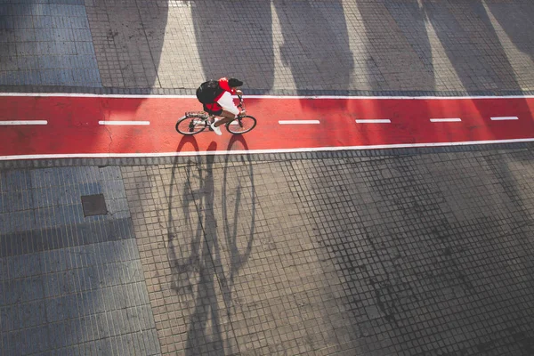 Ciclista andando na pista de bicicleta urbana vermelha em Las Palmas de Gran Canaria, sombra de bicicleta. Conceito de ciclovia urbana . — Fotografia de Stock