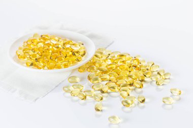 Akşam çuha çiçeği yağı kapsülleri, beyaz tabakta ve beyaz arka plana döküldü. Alternatif tıp ve sağlık hizmetleri kavramı.