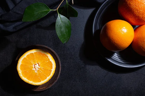 Oranges, orange slice and orange leaves on black textured background — Stock Photo, Image