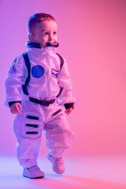 Amerikan astronot kıyafetleri giymiş, kırmızı ve mavi ışıkla aydınlatılmış renkli bir çocuk portresi. astronot ve çocuk konsepti.