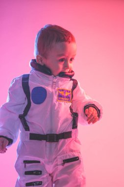 Amerikan astronot kıyafetleri giymiş, kırmızı ve mavi ışıkla aydınlatılmış renkli bir çocuk portresi. astronot ve çocuk konsepti.