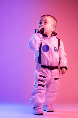 Amerikan astronot kıyafetleri giymiş, kırmızı ve mavi ışıkla aydınlatılmış renkli bir çocuk portresi. astronot ve çocuk konsepti.