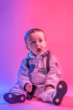 Amerikan astronot kıyafetleri giymiş, kırmızı ve mavi ışıkla aydınlatılmış renkli bir çocuk portresi. astronot ve çocuk konsepti.