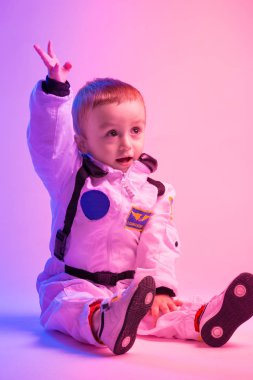 Amerikan astronot kıyafetleri giymiş, kırmızı ve mavi ışıkla aydınlatılmış renkli bir çocuk portresi. astronot ve çocuk konsepti.