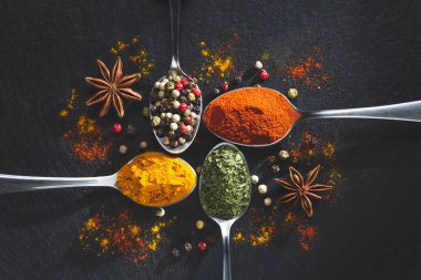 Yıldız anis ve kaşık biber, paprika, maydanoz ve zerdeçal ile siyah arka planda fotokopi alanı, üst manzara. Yemek malzemeleri ve baharat konsepti.
