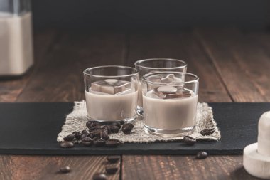 Glasses of Cream coffee liqueur with ice, and coffee  beans on rustic wooden background. clipart