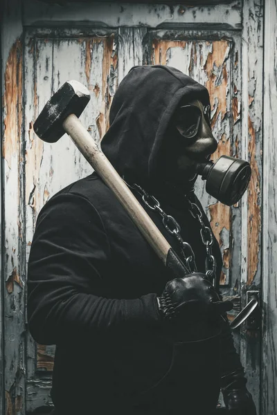 Man with gas mask and a hammer in machine room. Nuclear, Biological and Chemical danger concept.