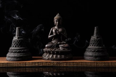 Budist çanları ve tütsü dumanıyla meditasyonda oturan Buda heykeli. Zen ve meditasyon kavramı.