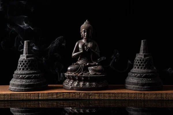 Statue of Buddha sitting in meditation, with buddhist bells and incense smoke. Zen and meditation concept.