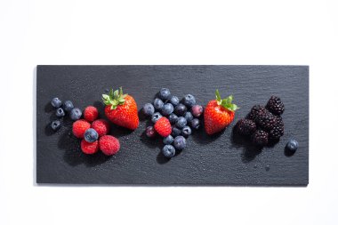 Beyaz arka planda bir levhada taze meyveler. Üst görünüm.