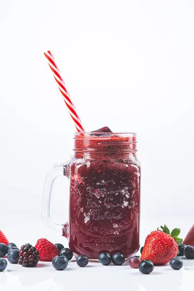 白い背景に藁と赤い果実のミックスを持つガラス瓶の中の赤いフルーツスムージー — ストック写真