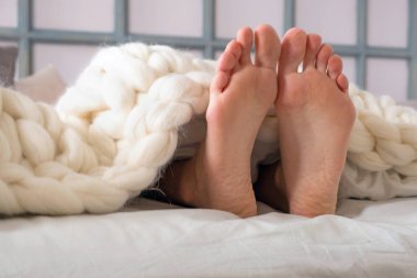 Örgü örülmüş beyaz merino yününden iki bacak sarkıyor.