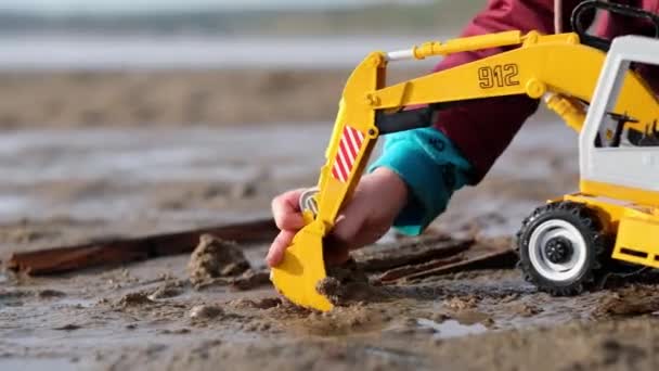 Игрушечный экскаватор, копающийся во влажном песке — стоковое видео