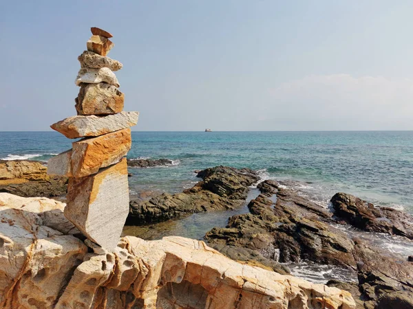 Balancing stones with each other on a rocky sea shore.