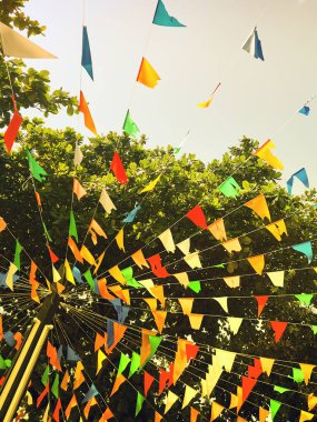 Gökyüzüne karşı yeşil yapraklar üzerinde küçük bayraklar. Ağaçlar arka plan.