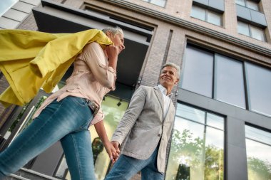 Mutluluğu seçiyoruz. Şehir caddesinde yürürken el ele tutuşup gülümseyen sevimli orta yaşlı çift.