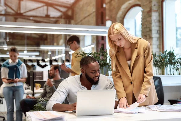 Together we can achieve more. Young afro american cheerful man discussing new project with his beautiful female colleague while working together in the modern office — Stock Photo, Image