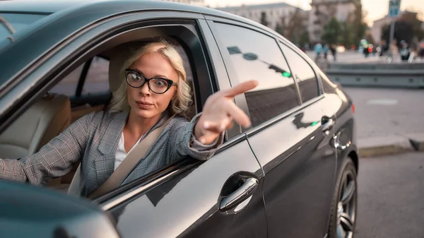 Feeling angry. Portrait of angry business woman gesturing with hands and arguing with somebody while driving a car