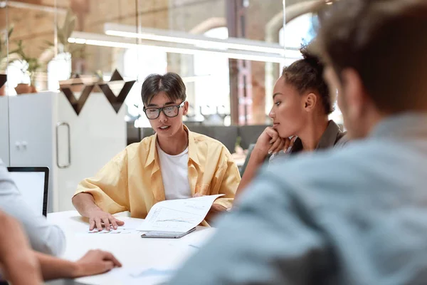 Equipa do projecto. Jovem asiático homem discutindo algo com seus jovens colegas enquanto trabalham juntos no escritório moderno — Fotografia de Stock