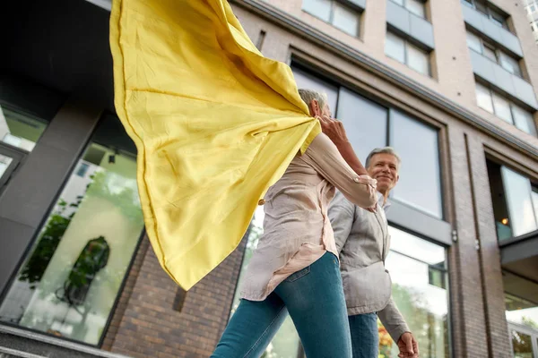 Andiamo a fare shopping oggi. Felice coppia di mezza età che si tiene per mano mentre cammina insieme per la strada della città . — Foto Stock