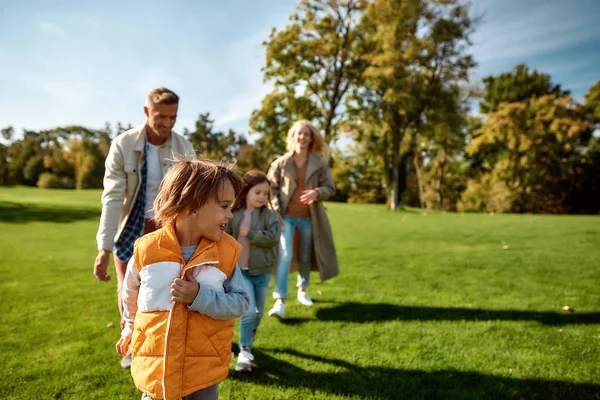 Ha kul. Spännande familj springer utomhus på en solig dag — Stockfoto