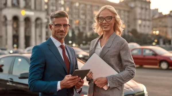 Criar uma parceria de negócios de sucesso. Dois colegas alegres no elegante desgaste clássico olhando para a câmera e sorrindo enquanto estão ao ar livre — Fotografia de Stock